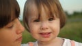 Small child in arms of her sister smiles and shows her finger in camera, family walk in park in the summer, slow-motion Royalty Free Stock Photo