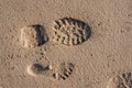 Small child bare foot print on a warm sand and adult shoe print. Summer holiday and time concept. Copy space. Day on a beach. Royalty Free Stock Photo