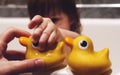 A small child bathes in the bathroom and holds a rubber yellow duck in his hand. a mother holds a child`s hand in the bathroom. se Royalty Free Stock Photo