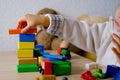 Small child, blonde girl 3 years old plays toys, builds towers and buildings from colored wooden figures, concept of housing Royalty Free Stock Photo