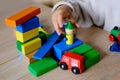 Small child, blonde girl 3 years old plays toys, builds towers and buildings from colored wooden figures, concept of housing Royalty Free Stock Photo