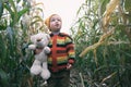 Small child boy in knitted sweater with his friend toy taddy bear exploring nature together. Cute smiling toddler kid playing in