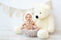 A small child a boy is sitting in a basket in a bear hat with a large Teddy bear Royalty Free Stock Photo