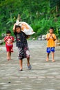 Small child carrying a huge heavy sack.