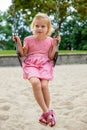 Small kid on swing. Beautiful little girl swinging at playground in park in summer Royalty Free Stock Photo