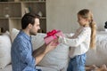 Small child daughter giving wrapped gift box to young father.