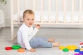 A small child does not want to study, a frustrated baby boy 2 years old sitting with toys, early development