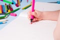 A small child draws with a pink felt-tip pen a heart in an album Royalty Free Stock Photo