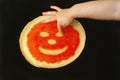 A small child draws a smiling face from fish ROE on a fried pancake, which lies on a black background. a cheerful face made of cav Royalty Free Stock Photo