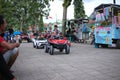 A small child driving a mini car that is controlled using a remote control by his parents