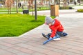 A small child fell from a scooter and is trying to climb, walking children in the park