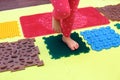 Small child with a flat-bottomed stomach goes barefoot on an orthopedic foot mat for the appointment of an orthopedist. gymnastics