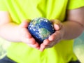 Small child in a green T-shirt holding the planet Earth in her hands. Earth day. Green concept Royalty Free Stock Photo