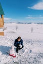 Small child helps his dad build a snowman in the snowy yard of the house. Back view Royalty Free Stock Photo