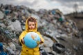 Small child holding globe on landfill, environmental pollution concept. Royalty Free Stock Photo