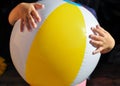 A small child holding an inflatable ball with a yellow stripe on a walk in the garden Royalty Free Stock Photo