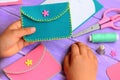 Small child holds a felt purse in his hand. Child shows a felt purse. Handcraft supplies on a wooden table