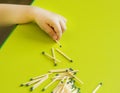 A small child holds a match in the hand on a green background, close-up, danger, fire, child and matches