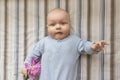 A small child holds a pink peony flower