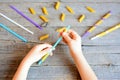 Small child holds straw and dried tube pasta in his hands. Child stringing pasta onto straw