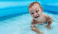 A small child in an inflatable kids round pool in sunny summer weather