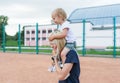 Small child, a little girl sits on the shoulders of mother smiling, laughing, playing, having fun at tennis court. Royalty Free Stock Photo