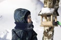 A small child looks into a birdhouse, winter day