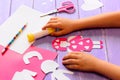 Small child made an angel doll of cardboard. Childrens hands on a wooden table