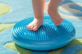 Little kid massages his feet while standing on the rug Royalty Free Stock Photo