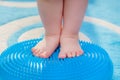 Little kid massages his feet while standing on the rug Royalty Free Stock Photo