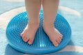 Little kid massages his feet while standing on the rug Royalty Free Stock Photo