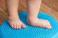 Little kid massages his feet while standing on the rug Royalty Free Stock Photo