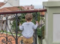 A small child observes something while holding on to railings