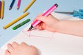 a small child painstakingly paints with a pink felt-tip pen a house in an album, Royalty Free Stock Photo