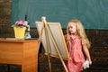Small child painting picture on studio easel. Girl in painting studio
