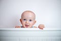 A small child peeks out on a white background. The child looks out of bed. peek-a-boo