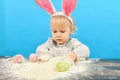 A small child with pink rabbit ears sculpts painted eggs in flou