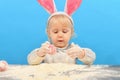 A small child with pink rabbit ears sculpts painted eggs in flou