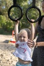 Small child on the playground. Playground. Mom helps the child to hanging on the rings