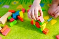 Small child playing with wooden blocks on green carpet Royalty Free Stock Photo