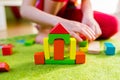 Small child playing with wooden blocks on green carpet Royalty Free Stock Photo