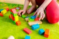 Small child playing with wooden blocks on green carpet Royalty Free Stock Photo