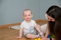 A small child plays on the floor with his mother in the constructor. The kid is looking directly at the camera Royalty Free Stock Photo