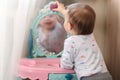 a small child plays in front of a toy mirror in the nursery