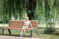 Small child plays in park. Kid is sitting on a park bench. Happy family and childhood concept. Healthy baby outdoors Royalty Free Stock Photo