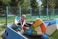 A small child rides in a boat a boy on rides in the summer in the park smiles Royalty Free Stock Photo