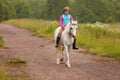 Small child riding on a white horse on the road Outdoors Royalty Free Stock Photo