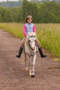 Small child riding on a white horse on the road Outdoors Royalty Free Stock Photo