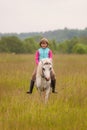 Small child riding on a white horse and smiling Outdoors Royalty Free Stock Photo