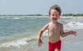 A small child runs along the seashore afraid of wave hair develop in the wind,